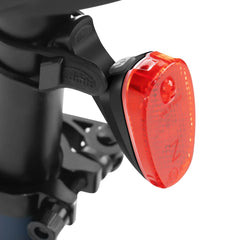 Red bicycle tail light attached to a black bike frame on a white background